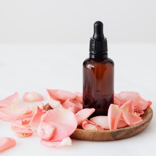 CBD Tincture Flavoring Guide with image of tincture bottle on bed of roses with wood platter